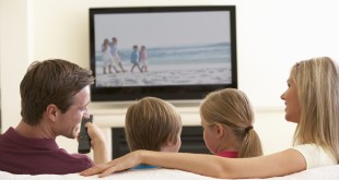 Family Watching Widescreen TV At Home